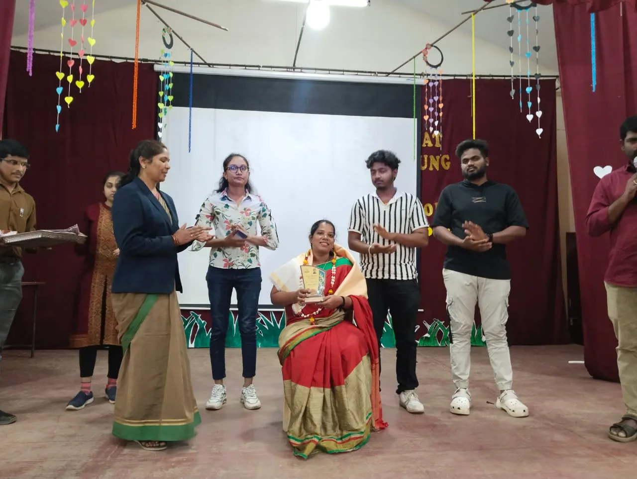 Mrs. Rita Marshall being felicitated with a memento at Don Bosco ITI Hassan while students applaud